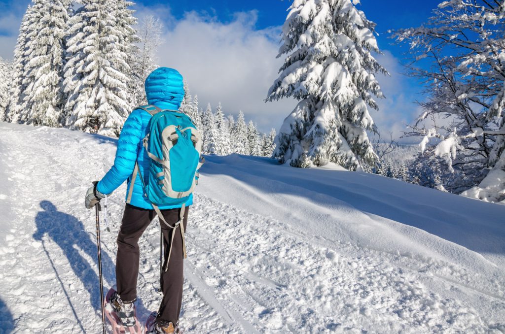 Young woman in dawn jacket hiking with snow shoes