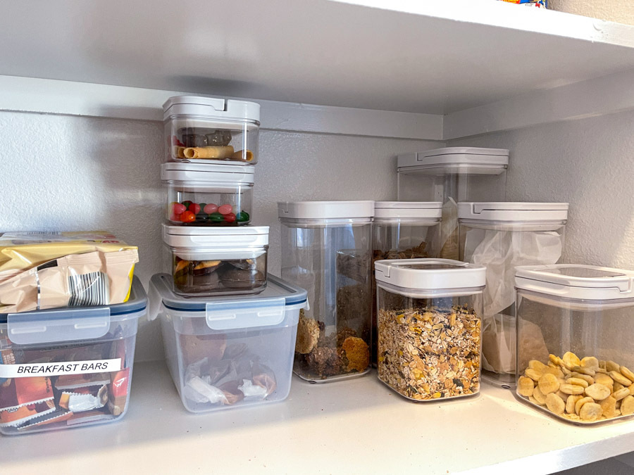 An organized pantry shelf with various types of cookies, cereal